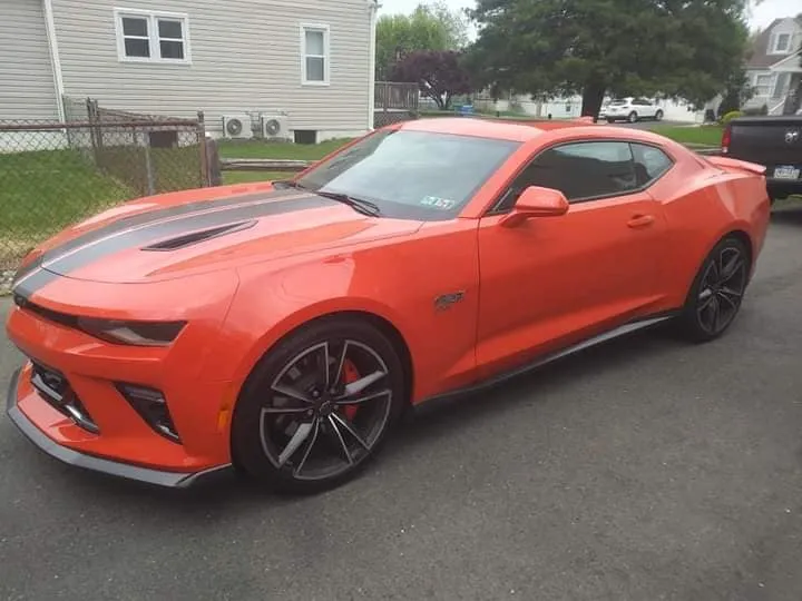 Orange Chevrolet Camaro SS with racing stripes after detailing